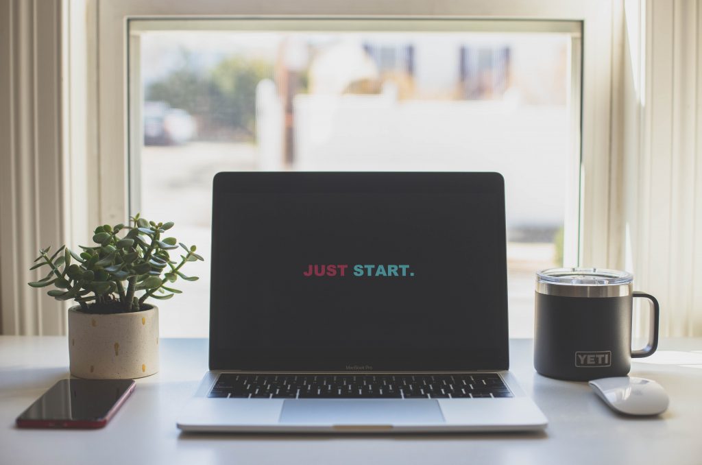 Macbook com a frase "Just start" na ela. É o que você tem que ter em mente para começar a escrever um livro hoje.